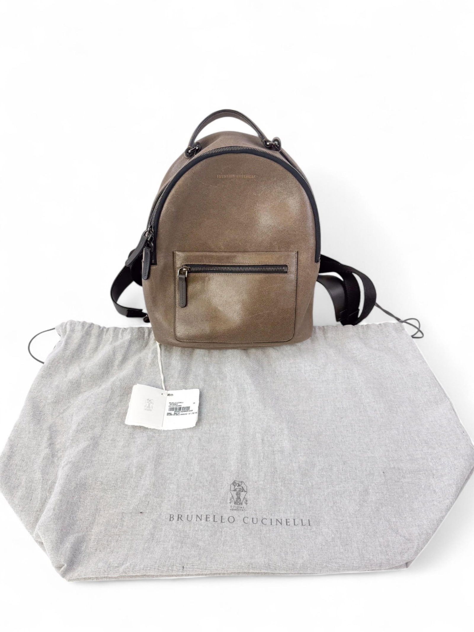 Brunello Cucinelli brown suede backpack.: A brown Brunello Cucinelli suede backpack with black leather trim, front zipper pocket, dual top zips, and adjustable straps. Gold logo stamp to front. Condition: Excellent.