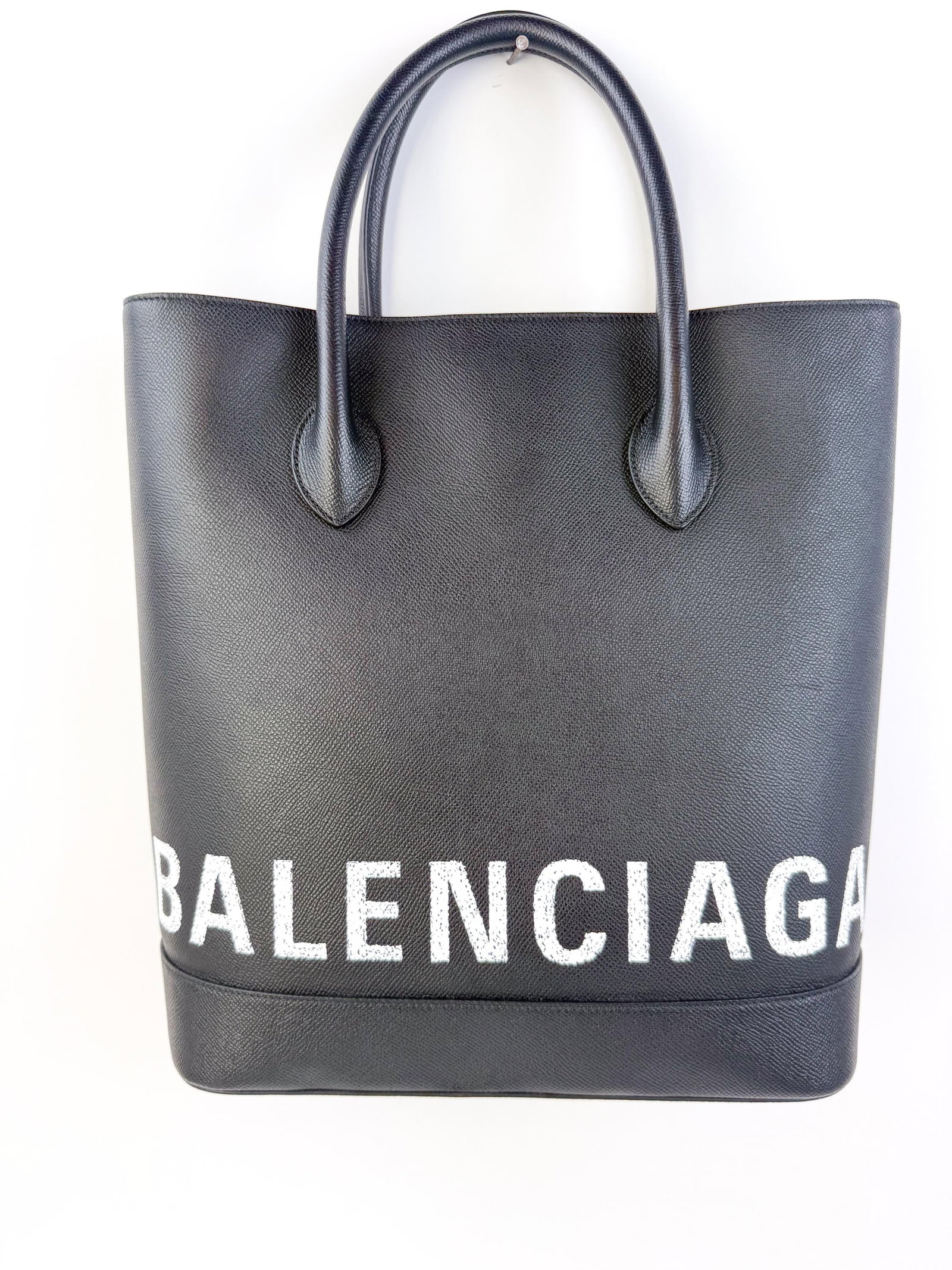 Balenciaga black leather logo tote.: A black Balenciaga leather tote with dual handles and oversized Balenciaga logo across lower body in white. Includes dust bag. Condition: Excellent.