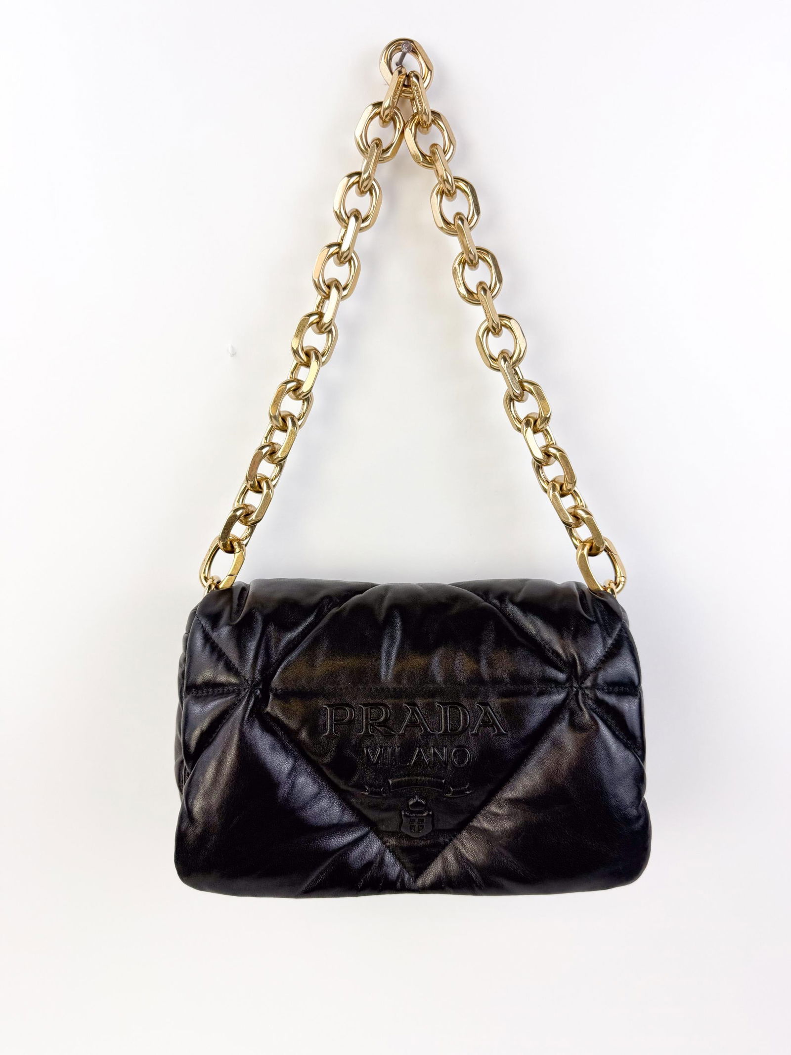 Prada black quilted leather shoulder bag.: A black Prada quilted leather shoulder bag with a triangular logo plaque embossed on the flap. Includes matching dust bag. Condition: Very good; minor handling wear consistent with gentle use.