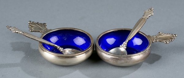 Pair of Georg Jensen salt cellars with spoons: A pair of Georg Jensen Denmark salt cellars with spoons. Cellars with enameled blue interiors. Marked sterling Denmark on all pieces. 1 .81 t ozs. Cellars: 1/2"h x 2 1/2"w. Spoons: 2 1/2"l.