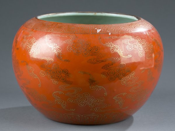 Orange Chinese porcelain bowl with gilt depiction: An orange glazed Chinese porcelain bowl with gilt depiction of bats among clouds. 20th century. 6 character reign mark on bottom. 5 1/2"h x 7 1/2"w.