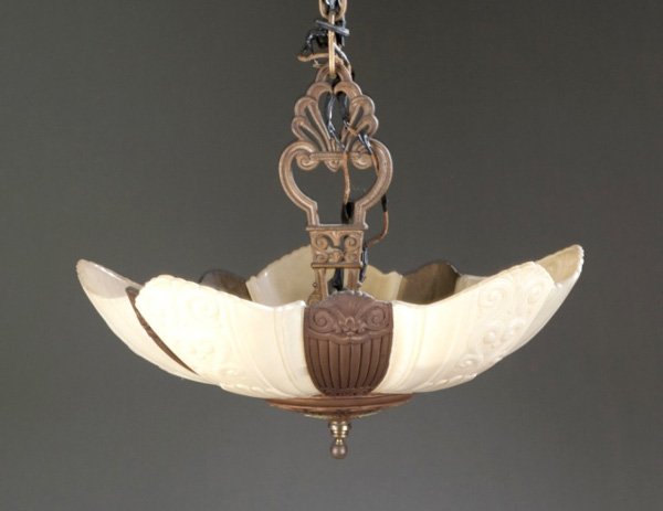 Arts and Crafts white glass hanging chandelier: An Art Deco bronze and slag glass hanging light. c.1920s-30s. Molded curved glass panels with relief scrolls. 15"h x 16"diam.