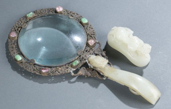 Jade handled magnifying glass and jade carving: A jade handled magnifying glass and a small carved jade beast. ++ Magnifying glass with metal frame with jade and hardstone beads. Handle flanked by bats. 7 1/4"l x 4"diam. ++ Cat-like beast: 1"h x 2 