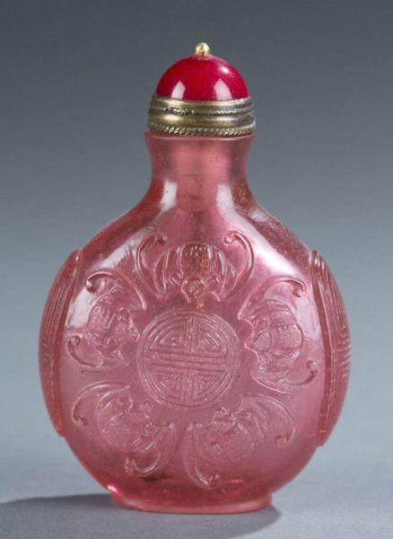 Pink Peking glass snuff bottle, c.1860-1900.: A carved pink Peking glass snuff bottle. c.1860-1900. Carved on both sides with bats and coins. Red Peking glass top with brass spoon. 2 1/4"h.