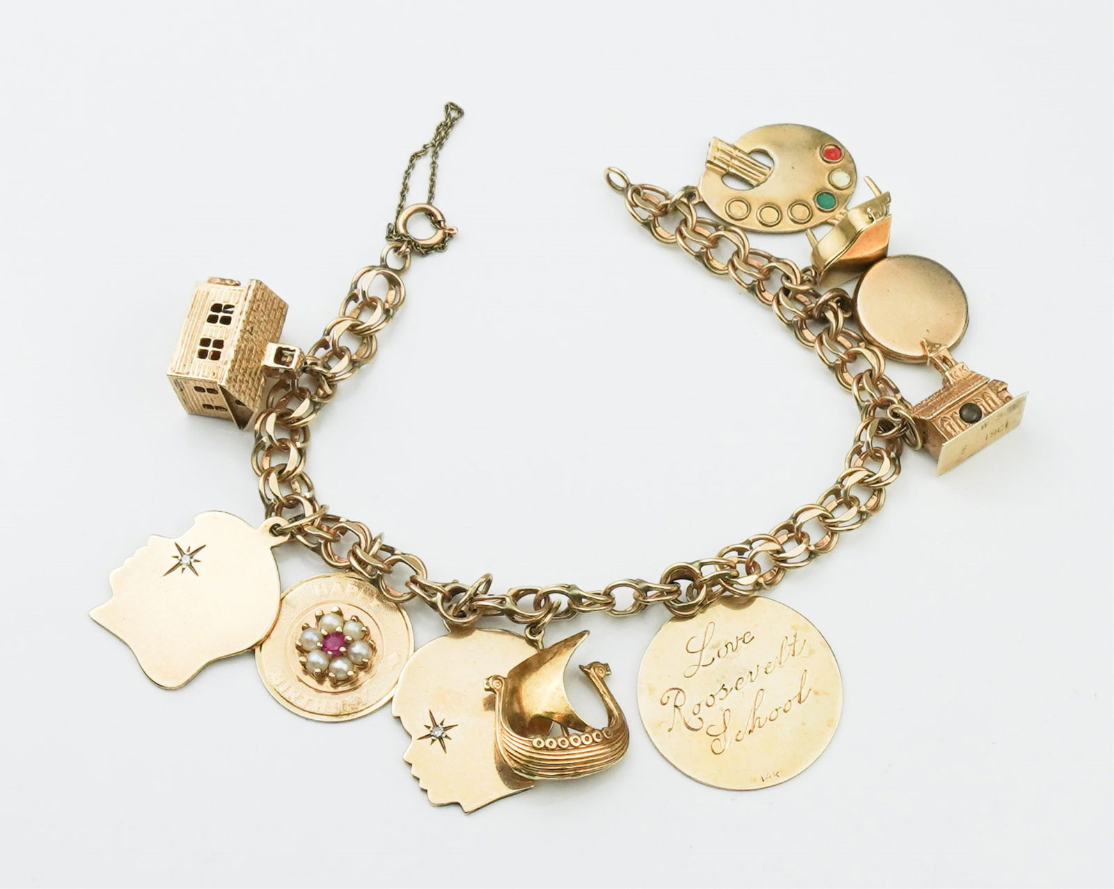 14KYG Charm Bracelet w/ Nine Charms: 14KYG Charm Bracelet w/ Nine Charms approx. 7 1/2 inches x 1/4 inch, charms to include school house, girl head, pearl & Ruby disc, boy head, Viking ship, monogrammed disc, church, locket, piano, artis