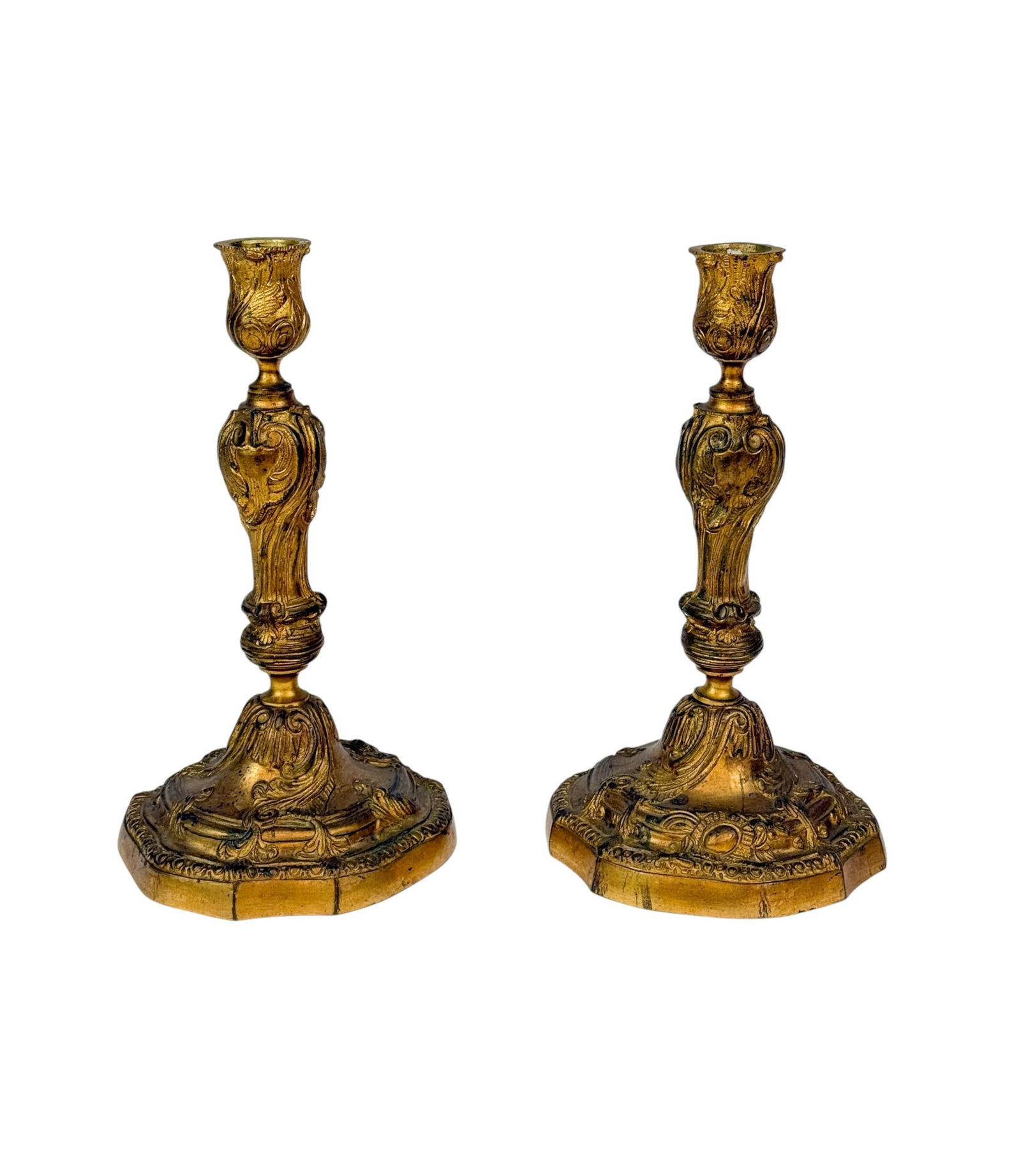 2 French Louis XV gilt candlesticks.: A group of two French Louis XV gilt candlesticks. 18th century. A matched pair of gilt bronze candlesticks in the Louis XV taste, each with a tulip-form socket above a baluster stem cast with scrollin