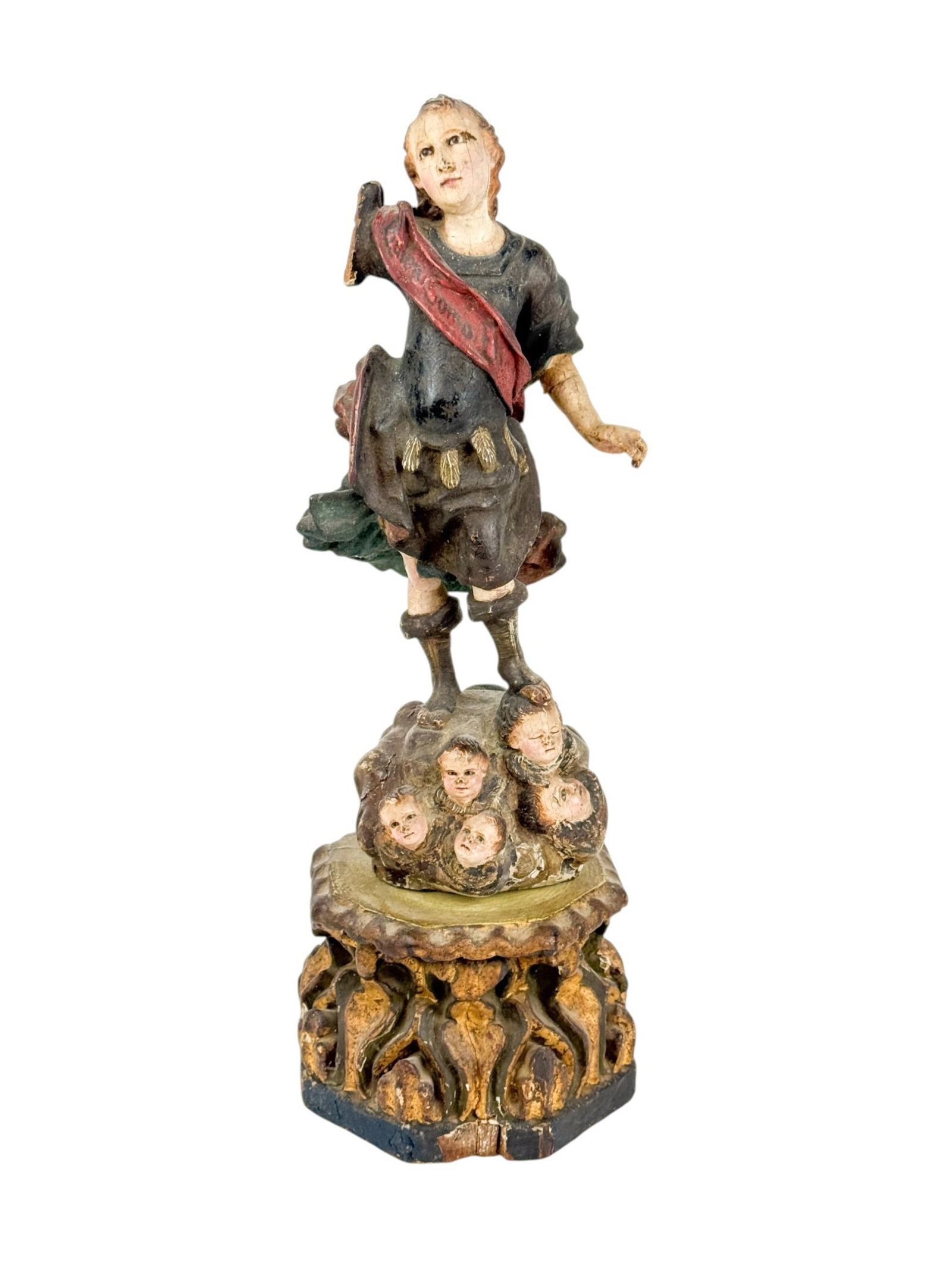 Carved wood St. Michael.: A carved wood Saint Michael wearing a sash reading "Quiem Como Dio (Who is like God)" and standing on various heads of cherubs. Figure: 13 1/4" x 6 1/4". Condition: Cracks, repaired break to arm,