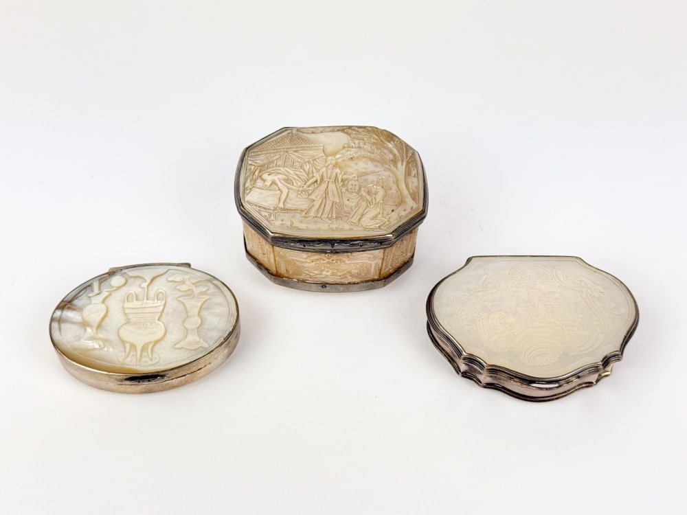 3 Mother of pearl snuff boxes: A group of three Continental mother-of-pearl snuff boxes, probably 18th?19th century, with silver-colored metal mounts. Comprising an oval box carved with vessels and a central tripod censer; a
