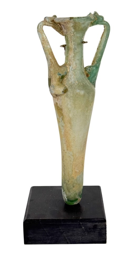 Byzantine Glass Amphoriskos: A Byzantine glass amphoriskos or miniature amphora of elongated spindle form, with a flaring mouth, narrow neck, paired handles and a tapering lower body, identified on the dealer documentation as Byz