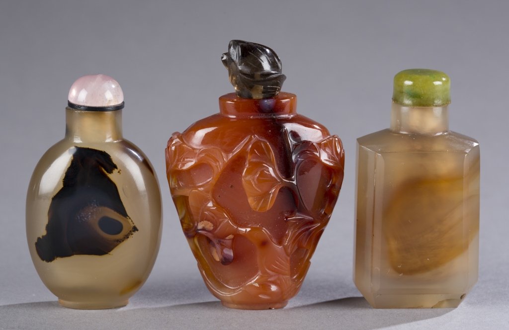 3 agate 19th century snuff bottles.: A group of three Chinese agate snuff bottles. 19th century. ++ Vasiform carnelian having carved relief decoration of floral pattern. 2 1/4" ++ Flattened octagonal form with inclusion. 1 1/8". ++ Silho