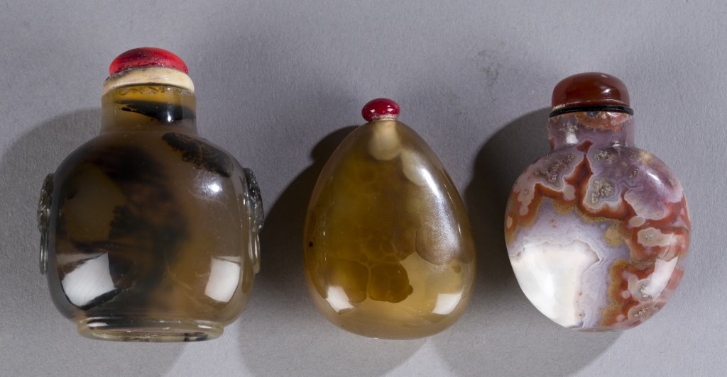 3 agate 19th century snuff bottles.: A group of three Chinese agate snuff bottles. 19th century. ++ Silhouette agate with mock mask handles. 2". ++ Pebble form with small silhouette inclusions. 1 3/4". ++ Carnelian and quartz with large 