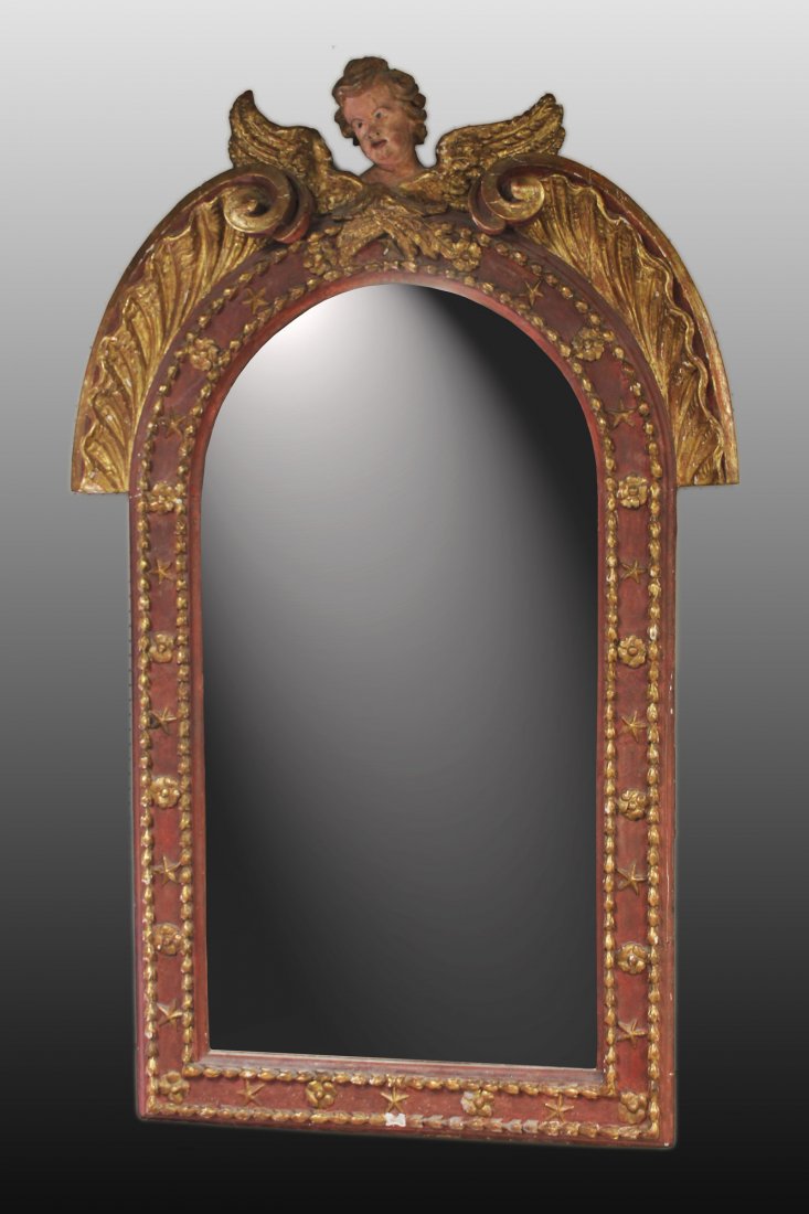 18th century Continental mirror with cherub: An wall mirror with carved cherub finial. 18th century. Having painted red accents with gilt decoration. Replaced "antiqued" mirror. 68" x 43".