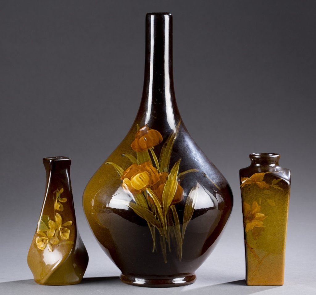 A set of 3 Owens vases. ++Small twisted bud vase,: A set of 3 Owens vases. ++Small twisted bud vase, brown high gloss glaze with flower motif. Impressed OWENSART, UTOPIAN and 115 on bottom. 5 3/4". ++Tall vase with a slender neck, brown high gloss