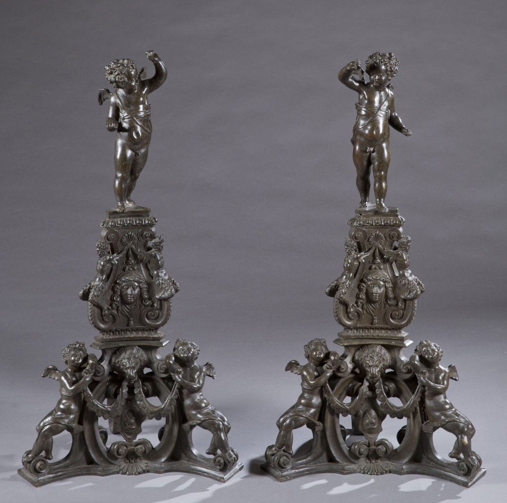 Two bronze andirons, 19th century.: A pair of two bronze putti andirons. 19th century. Rococo revival detail of centaurs flanking a female mask in relief supported by triangular form with additional putti in relief. 41 3/4"h x 20"w.