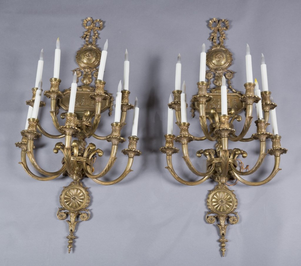 Pair of George III style bronze wall sconces.: Pair of George III style nine-light electrified wall sconces. Late 19th century. Backplate with rosette box, classical frieze and urn motif issuing two tiers of leaf form C-scroll arms terminating in 