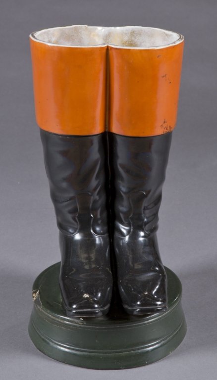 Riding boots umbrella/cane stand.: An ironstone riding boots umbrella stand. Early 20th century. Glazed in rust, black and dark green, with gold rim, On a circular base. 2" piece missing on left side of base. 21"h.