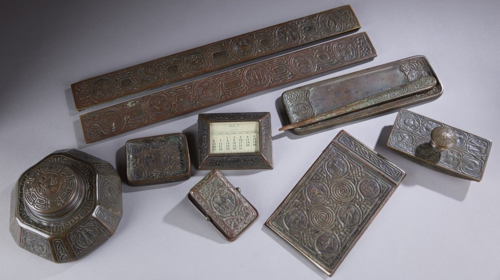 9 piece Tiffany Studios zodiac desk set.: A Tiffany Studios nine piece desk set. c.1897-1918. Having a dark brown and green patina and comprising of an inkwell numbered 1072, desk calendar numbered 929, a rocking blotter numbered 990, a lette