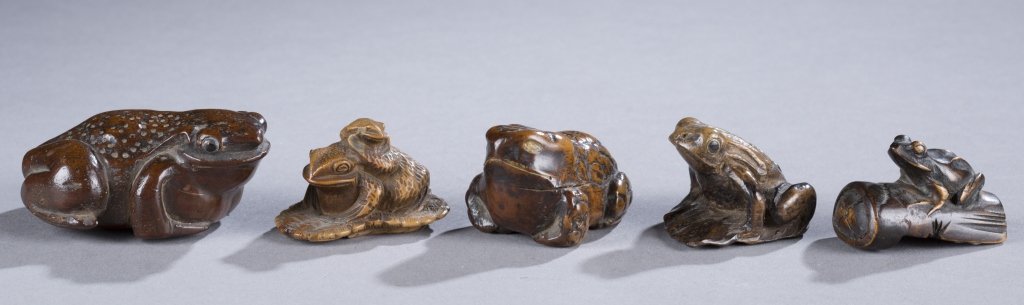 A Group of 4 Frog Netsuke: A group of 4 wood netsuke of toads and frogs.++ Toad. 2 1/4".++ Mother toad w/ baby toad on its back. 1 3/4".++ Toad 1 3/4". Toad on a leaf. 1 1/2". Frog on a log. 1 1/2".