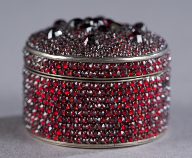 Russian Pill box w/ garnets.: A small Russian pill box decorated in it's entirety of red garnets of various sizes. Marked on inside center with hallmark. 1" x 1 1/2". Condition: Box has had past repairs to surface with re-applicat