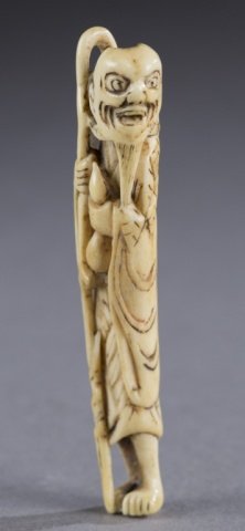 A Japanese stag antler sashi netsuke of a sennin: A Japanese stag antler sashi netsuke of a sennin. 18th century. Figure grasping a staff, wearing a mugwort cloak, and holding a gourd. Himotoshi on the back.. 9.7cm. Provenance: The Humphrey collectio