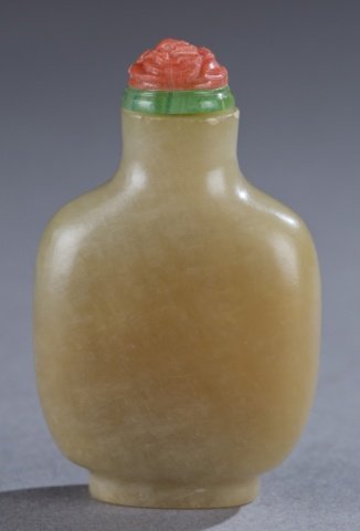 A Chinese soapstone snuff bottle.: A Chinese soapstone snuff bottle. 19th century. Of flattened rounded rectangular form with a raised oval foot rim, and flared neck. Flowered carved redd glass with geen collar stopper. Provenance: The