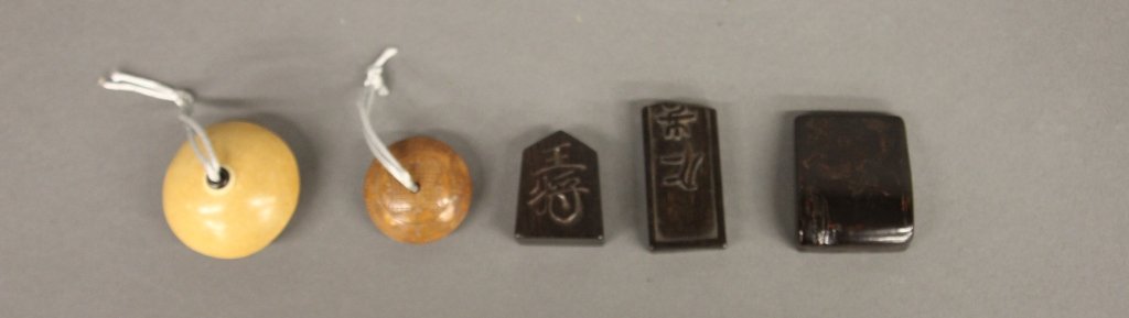Group of 5 netsukes.: A group of 5 netsukes. Wood. ++ Light tan with carved circular design in a darked wood on bottom. 1 1/4"h x 2"diam. ++ Carved brown wood with design of a flower on top and a design of a landscape n th