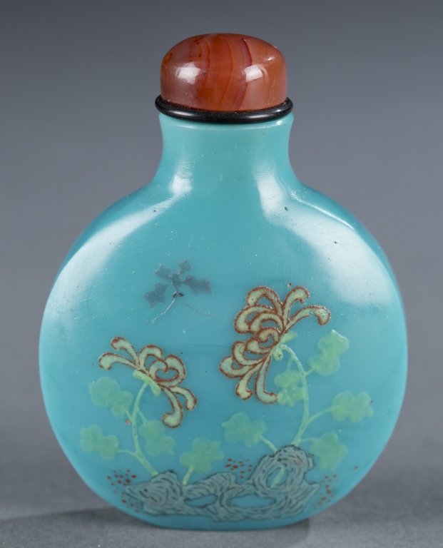Blue glass Chinese snuff bottle, enamel decoration: A Chinese blue glass snuff bottle with enamel design. C.1769. Flattened round form with flowers and butterfluy on the front with peom and date on the reverse. Having a carnelian stopper. 2 1/2". Prove