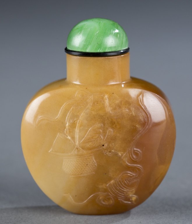 Chalcedony Chinese snuff bottle.: A chalcedony Chinese snuff bottle. c.1750-1860. Spade form with a straight neck, relief carved with Buddhist emblems and a jade cabochon stopper. 2". Provenance: From a Private Collection in Humphrey,
