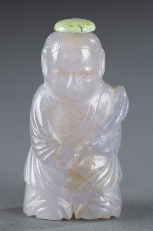Chinese chalcedony snuff bottle.: A Chinese chalcedony snuff bottle. Late19th/Early 20th century. Light purple-blue carved into figure of a boy. 2 3/8".