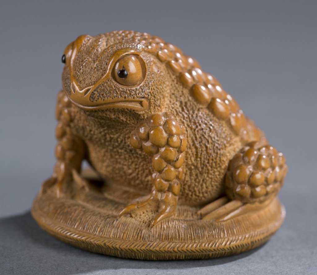 Japanese wood netsuke of a toad with bulging eyes.: A Japanese boxwood netsuke of a toad with bulging eyes. 19th century. Signed Jyu kyo in sosho. Seated on a coiled straw mat, bottom with large himotoshi and signature on unusual reserve. From the Ise