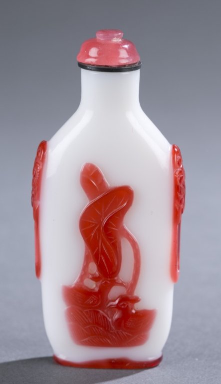 Chinese red on milk white overlay snuff bottle.: A Chinese red on milk white overlay snuff bottle. c.1750-1820. Design of fish spraying fountain of water on one face, and lotus on the reverse, shoulders with mock mask handles. Having a carved carnel