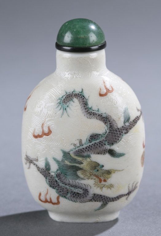 Chinese porcelain snuff bottle w/ enameled dragon: A Chinese porcelain snuff bottle with enameled dragon. C.1874-1900. Rounded rectangular form with all over incised clouds, and enameled green dragons chasing flaming pearl. Having a serpentine cabocho