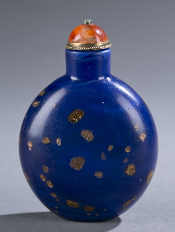 Chinese blue glass snuff bottle, aventurine spots: A Chinese blue glass with aventurine splashes snuff bottle. c.1750-1820. Round form with a straight neck on concave foot. Having a carnelian caboshon in metal stopper with jade finial. 2 7/8". Morriso