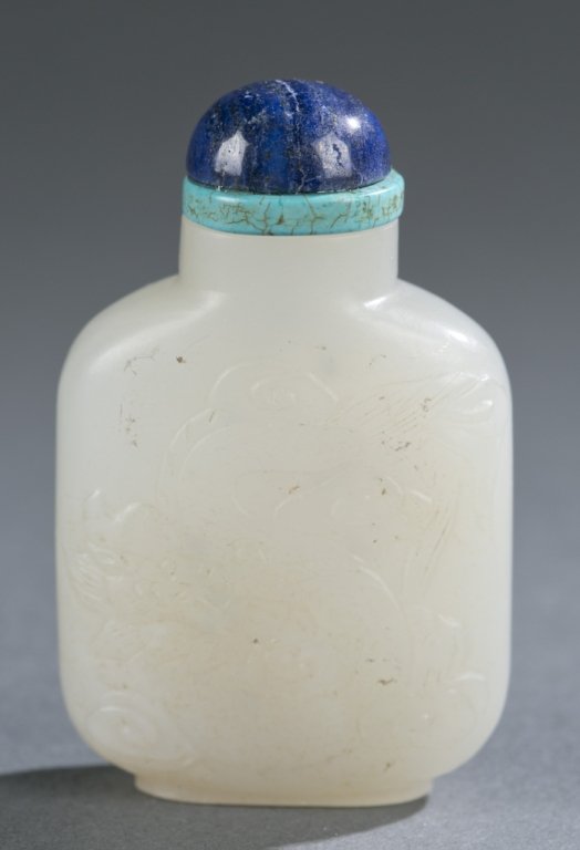 Chinese white jade snuff bottle, phoenix/dragon: A Chinese white jade snuff bottle. 19th century. Low relief carving of phoenix on one side, and dragon on the other. Of rounded rectangular form, well hollowed, with raised foot rim and straight neck.