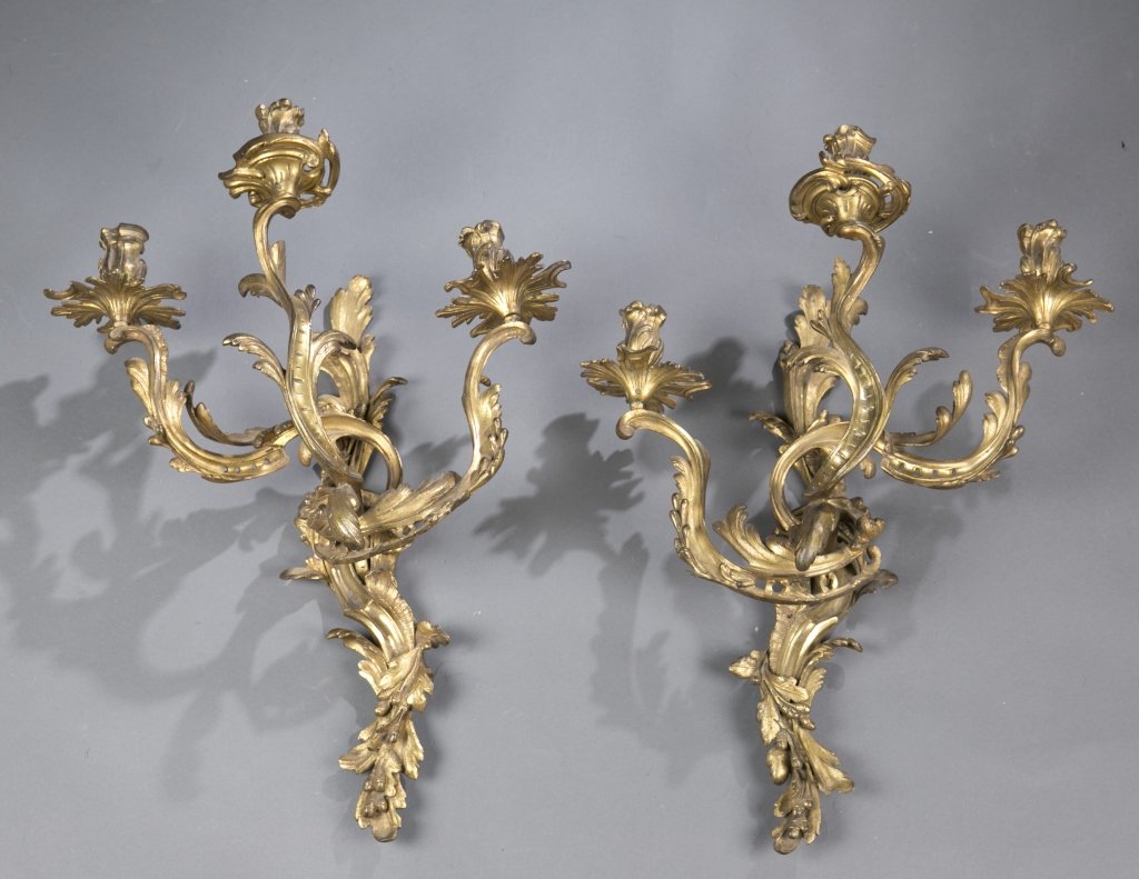 Pair of Louis XV style bronze 3 light wall sconces: A pair of Louis XV style gilt bronze three light wall sconces. Late 19th century. Gilt bronze in a rocaille C-scroll leaf arms and flower candle holders. 24 1/2"h x 18"w x 8 1/2"d.