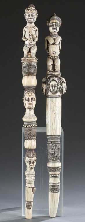 2 African carved ivory scepters.: A group of 2 African carved ivory scepters. ++ Carved and incised scepter with two male heads and full male figure at top. 20 1/4"L. ++ Carved and incised scepter with female faces topped with full fe