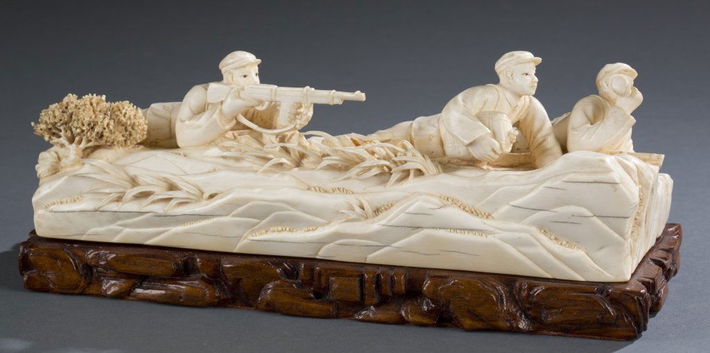 Chinese Cultural Revolution ivory figural scene.: A Chinese Cultural Revolution ivory figural scene. 1960s. Carved ivory scene of 3 soldiers in the prone position on a carved hardwood base. 4 3/8"h x 10 1/4"w x 4"d. Bidders should be aware of the cha
