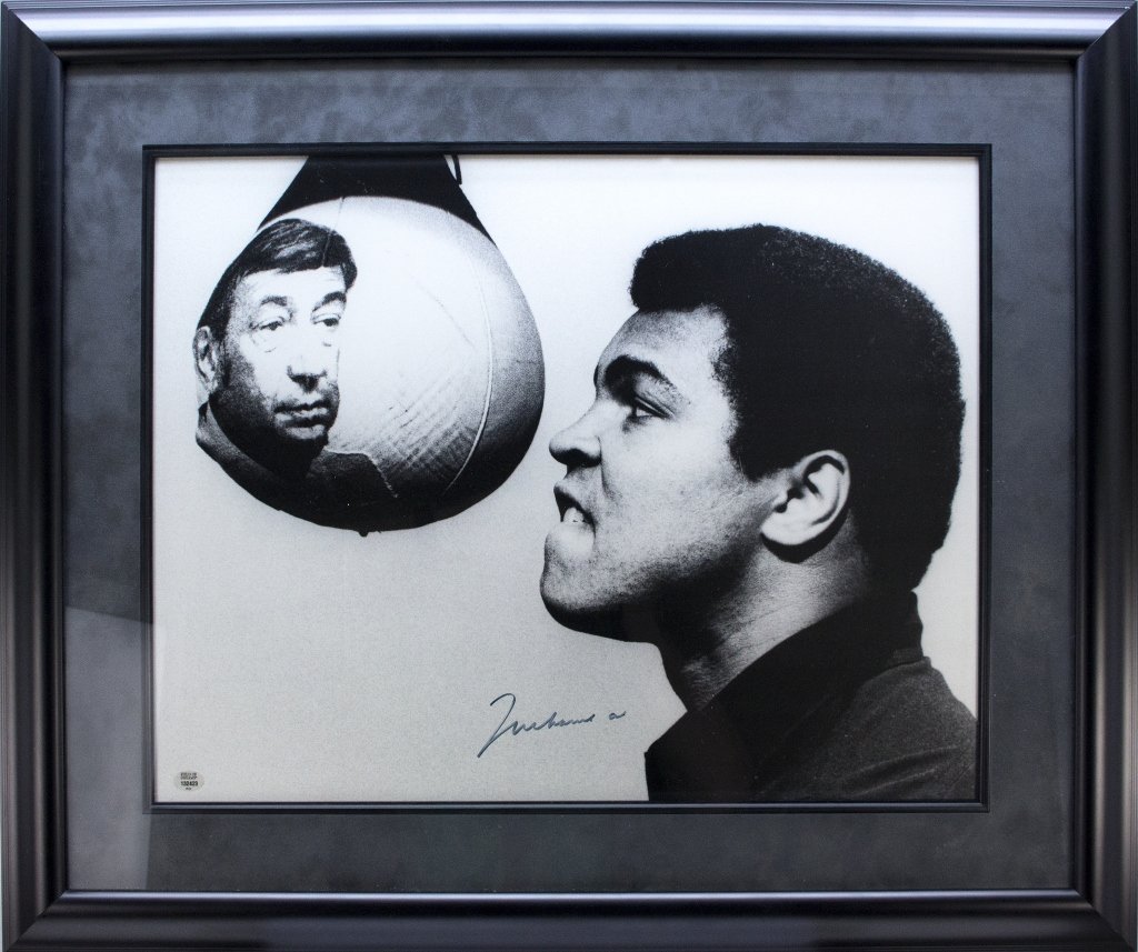 Muhammad Ali: Signed poster.: [Ali, Muhammad] Poster, signed by Muhammad Ali. Image is a printed photograph of Muhammad Ali seeing his reflection in a punching bag. “Field of Dreams” sticker in image at lower left. 15 ¼” x 