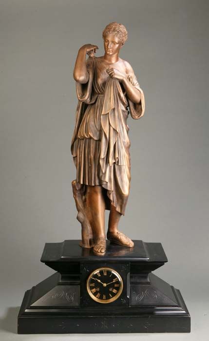 Spelter statue of a Greek goddess supported on a: Spelter statue of a Greek goddess supported on a clock base veneered with black stone and weighted having scratch scrolled carving, 20th century, 38"h. x 21 1/2"w. x 9 1/2"d. This is a live auction at