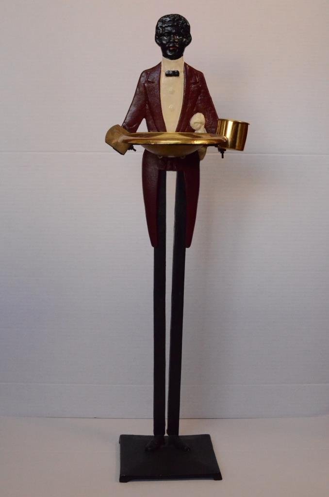 Black Americana Cast Iron & Brass Smoking Stand: [Smoking/Smoking Stand]. Figural painted cast iron and brass smoking stand of Black butler. Includes a brass ashtray, matchbox holder and cup for cigarettes or matches. 33" H X 10" W x 9" D. Red paint