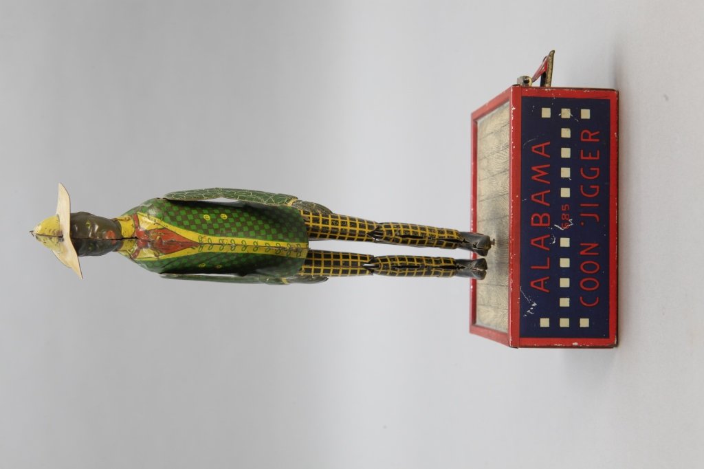 Lehmann "Alabama Coon Jigger" Tin Windup Toy: [Toys/Windup Toy]. Lehmann "Alabama Coon Jigger" windup toy. Made in Germany, patented May 24, 1910. Figure dressed in green checked jacket and black/yellow checked pants w/ yellow hat. In working con