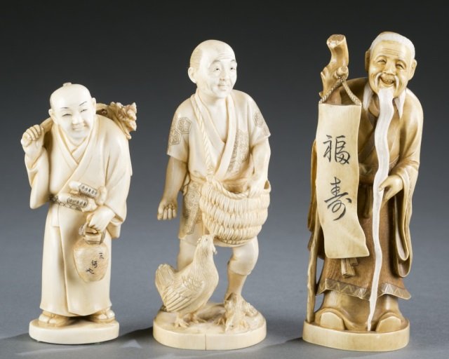 Group of 3 Japanese African elephant ivory okimonos.: A group of three Japanese okimonos. ++ Man carrying a tree branch with Daisho (pair Japanese sword) and a wine jar. Mark on the bottom: "Tamano". ++ Man feeding chicken, carrying a basket. Mark on the