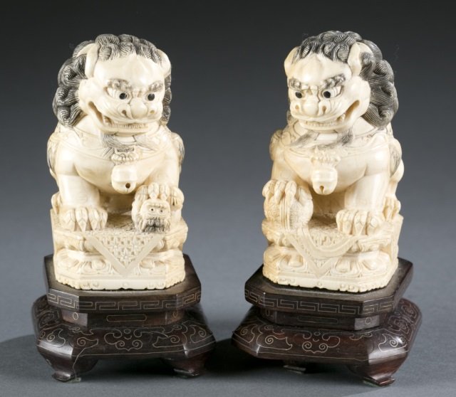 Pair of Chinese carved ivory Fu lions.: A pair of Chinese carved ivory Fu lions with stand. One Fu/Guard lion holding a ball, the other one holding a baby lion under its front paws. 3 1/2"h, 5"h (with stand).