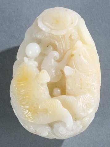 Chinese carved jade pendant of fish and lotus.: A Chinese carved jade pendant. Light russet and white jade. Carved with two carps playing pearls on lotus leaf design. 2 3/4"l x 2"w x 1 1/4"d.