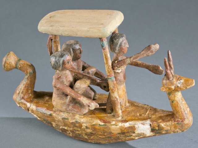 Egyptian style boat model for the afterlife.: An polychrome Egyptian style boat model for the afterlife. Early 20th century. 8"h x 12 1/2"l x 3 3/4"w. With wooden and glass display case: 13 1/2"h x 16"w x 9"d.Condition: Some chips and cracks to b