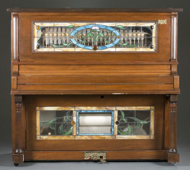 Goddess of Music player piano, c.1970s.: A Goddess of Music nickelodeon coin operated player piano by Carson City Parlor. With plaque from Monarch Piano Company, Chicago. c.1970s. Having a walnut body with inset floral stained glass. Comes w