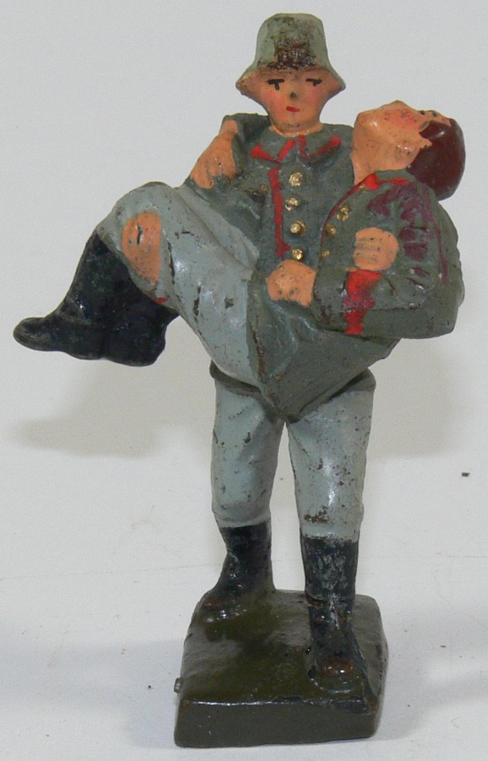 Lineol Soldat, einen verwundetetn Kameraden tragend.: Lineol Soldat, einen verwundetetn Kameraden tragend. Masse handbemalt. Gemarkt. 7 cm - Serie. Leichter Farbabrieb, sonst altersbedingt guter Zustand.