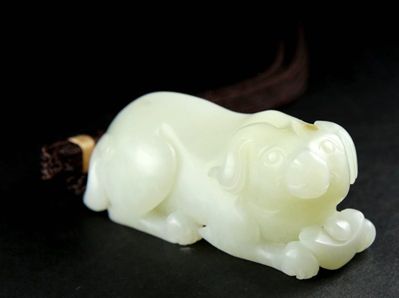 A WHITE JADE CARVING OF A DOG: Qing period. White jade carved a dog. 清代和田子料白玉狗