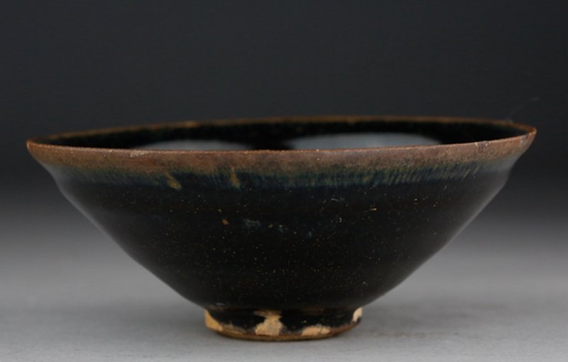 A SONG DYNASTY JIANYAO BROWN BOWL: With rounded sides and raised feet, the bowl evenly glazed in dark brown with lighter tone on the rm, and leaving the base white. H:5.5cm; D:12.8cm 宋代 建窑黑釉