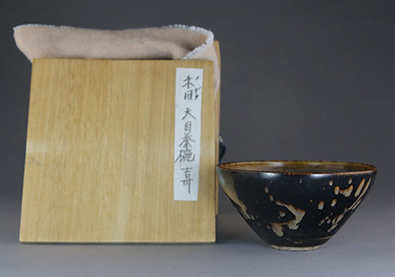 A SONG JIZHOU PAPER-CUT RESIST-DECORATED TEA BOWL: The interior decorated in resist technique with paper-cut decoration of three diamond-shaped, openwork flowers reserved in brown against the variegated, milky buff ground, the exterior covered in a 't